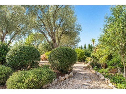 Verwunschener Privatgarten mit gepflastertem Wegenetz und mediterraner Begrünung
