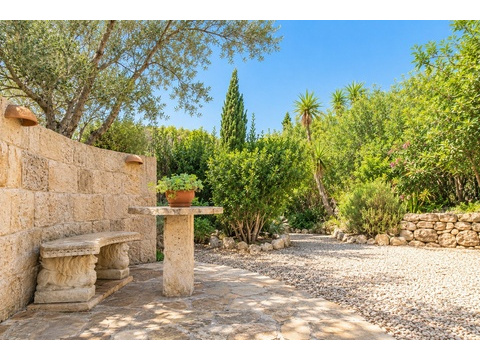 Idyllische Gartenlounge mit Natursteinmauern, eingebauten Sitznischen und mediterraner Begrünung