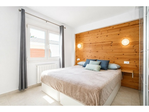 Helles Schlafzimmer mit Holzakzentwand und großzügigen Fensterflächenlichtern