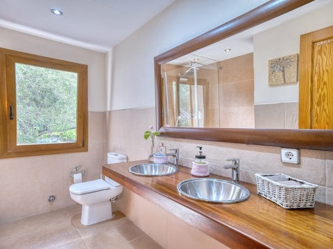 Elegantes Badezimmer mit Doppelwaschtisch, begehbarer Dusche und Fensterblick ins Grüne