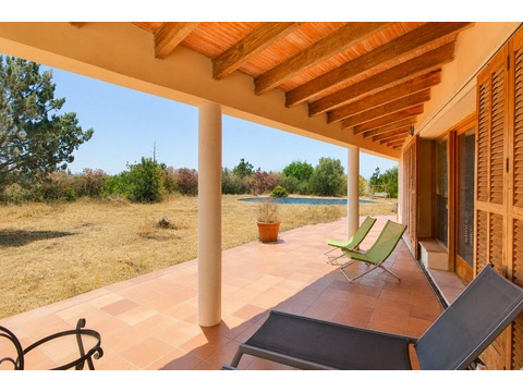Überdachte Terrasse mit tragenden Holzbalken und direktem Poolblick