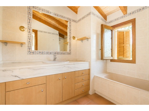 Badezimmer mit Marmor-Waschtisch, dekorativer Spiegelrahmung und Badewanne mit Fensterblick