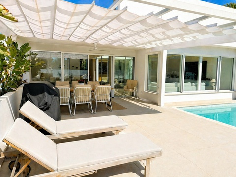 Poolbereich mit intelligenter Zonierung: Lounge-Bereich unter motorisierter Pergola und direkter...