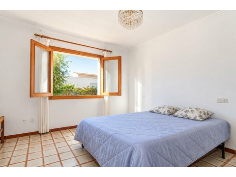 Helles Schlafzimmer mit Panoramafenster und Ausblick ins Grüne