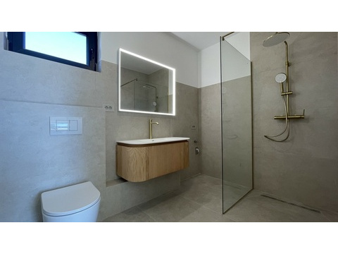 Badezimmer mit Regendusche und beleuchtetem Spiegel