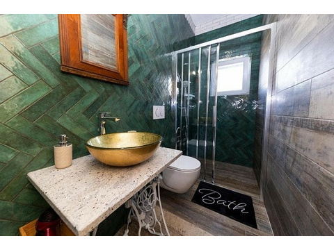 Badezimmer mit Dusche und grünen Fliesen