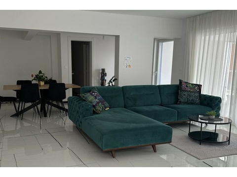 Wohnzimmer mit Ecksofa und großen Fenstern