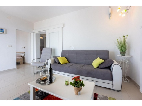 Wohnbereich mit Sofa und offenem Zugang zum Schlafzimmer