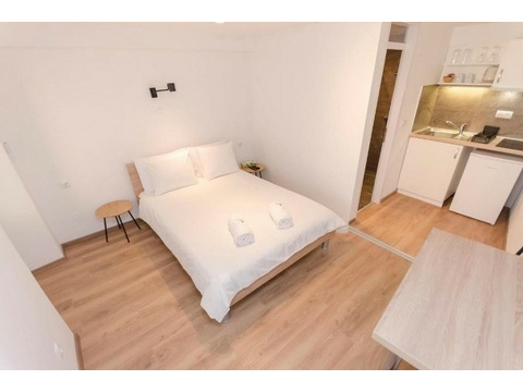 Schlafbereich mit Doppelbett und kleiner Küche im Appartement