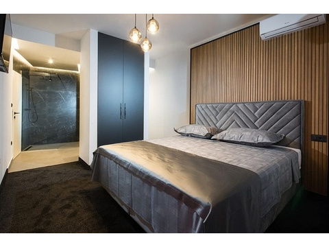 Schlafzimmer mit Holzpaneelwand und integriertem Duschbad