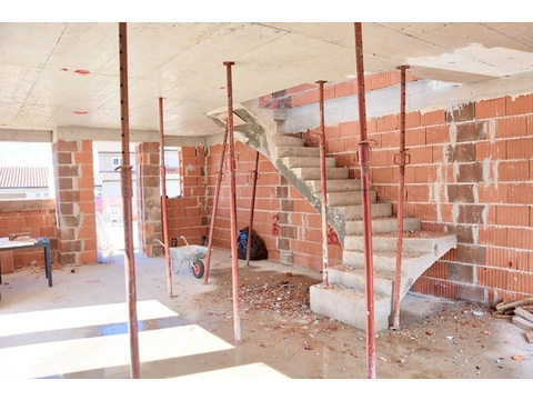 Innenansicht der im Bau befindlichen Doppelhaushälfte mit Betontreppe und Ziegelwänden