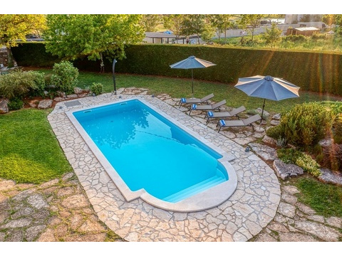Pool mit Sonnenliegen, Schirmen und Rasen