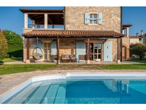 Hausfassade mit Terrasse hinter dem Pool