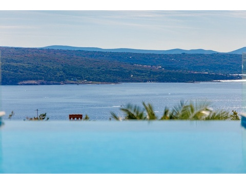 Überdachter Essbereich mit Barbecue Grill und Blick auf den Pool sowie das Meer.