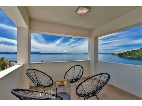 Überdachte Terrasse mit Sesseln und Meerblick