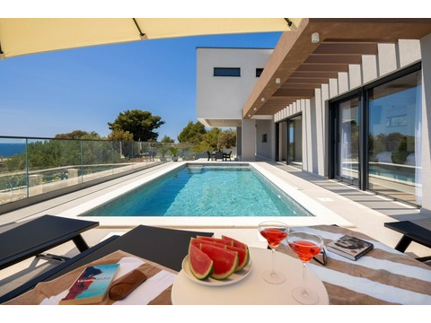 Pool mit Sonnenliegen und Blick auf das Meer