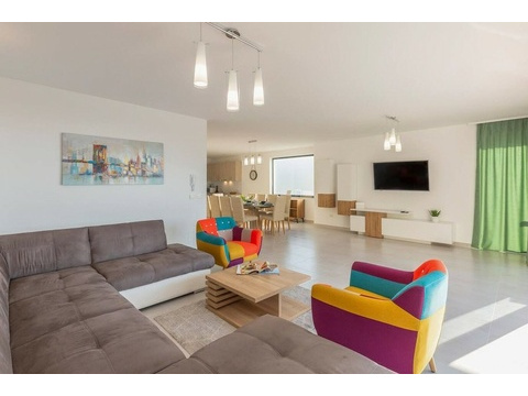 Wohnzimmer mit Ecksofa und bunten Sesseln