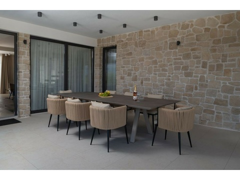 Überdachte Terrasse mit Esstisch und Natursteinwand