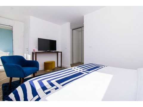 Schlafzimmer mit Sessel und Fernseher
