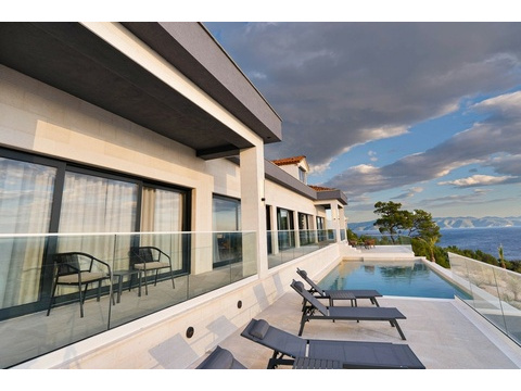 Terrasse mit Glasgeländer und Liegen am Pool