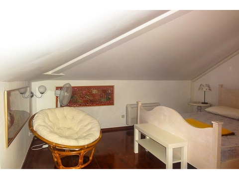 Dachzimmer mit Bett und Sessel