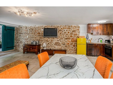 Esstisch vor Natursteinwand mit Fernseher