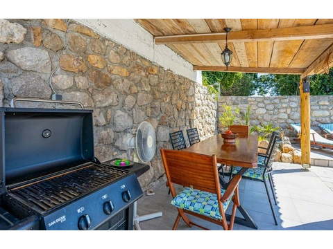 Überdachte Terrasse mit Grill und Esstisch