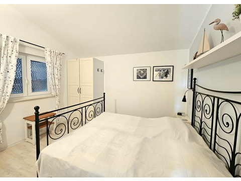 Schlafzimmer mit Doppelbett aus Metall unter der Dachschräge