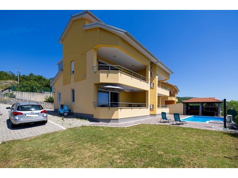 Gelbes Wohnhaus mit Parkplatz und Rasen