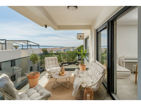 Überdachte Terrasse mit Sesseln und Blick zum Meer