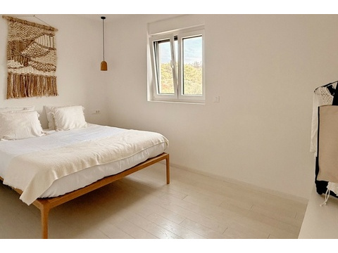 Zweites Schlafzimmer mit Holzbett und Fenster
